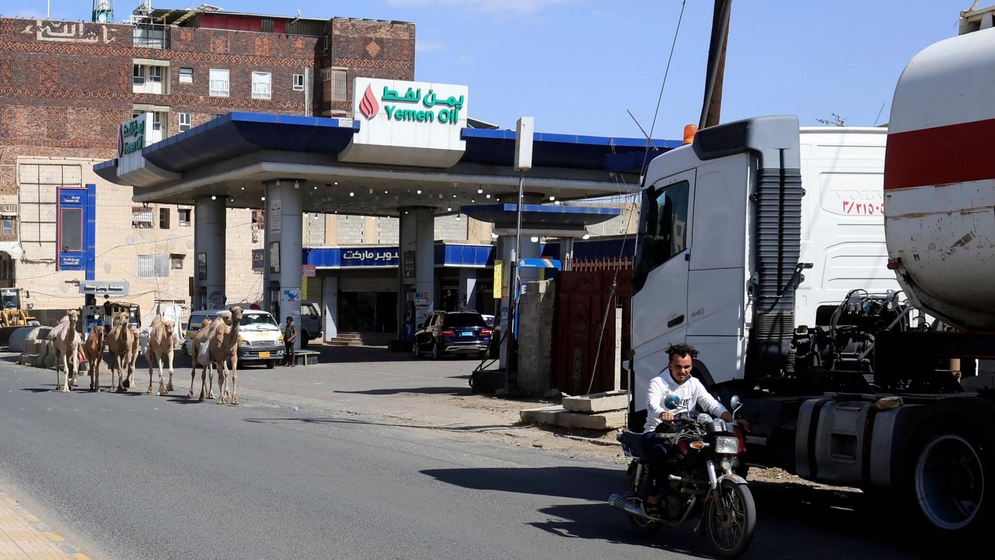 Man riding motorcycle past petrol station in Sanaa, Yemen