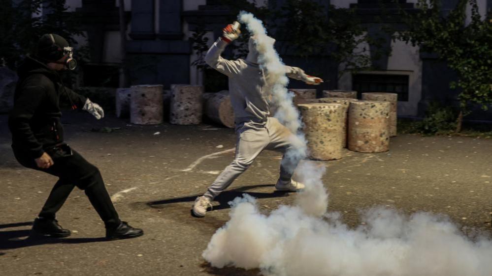 A protester throws a tear gas grenade back towards police during an anti-government protest in Tirana, Albania, October 19.