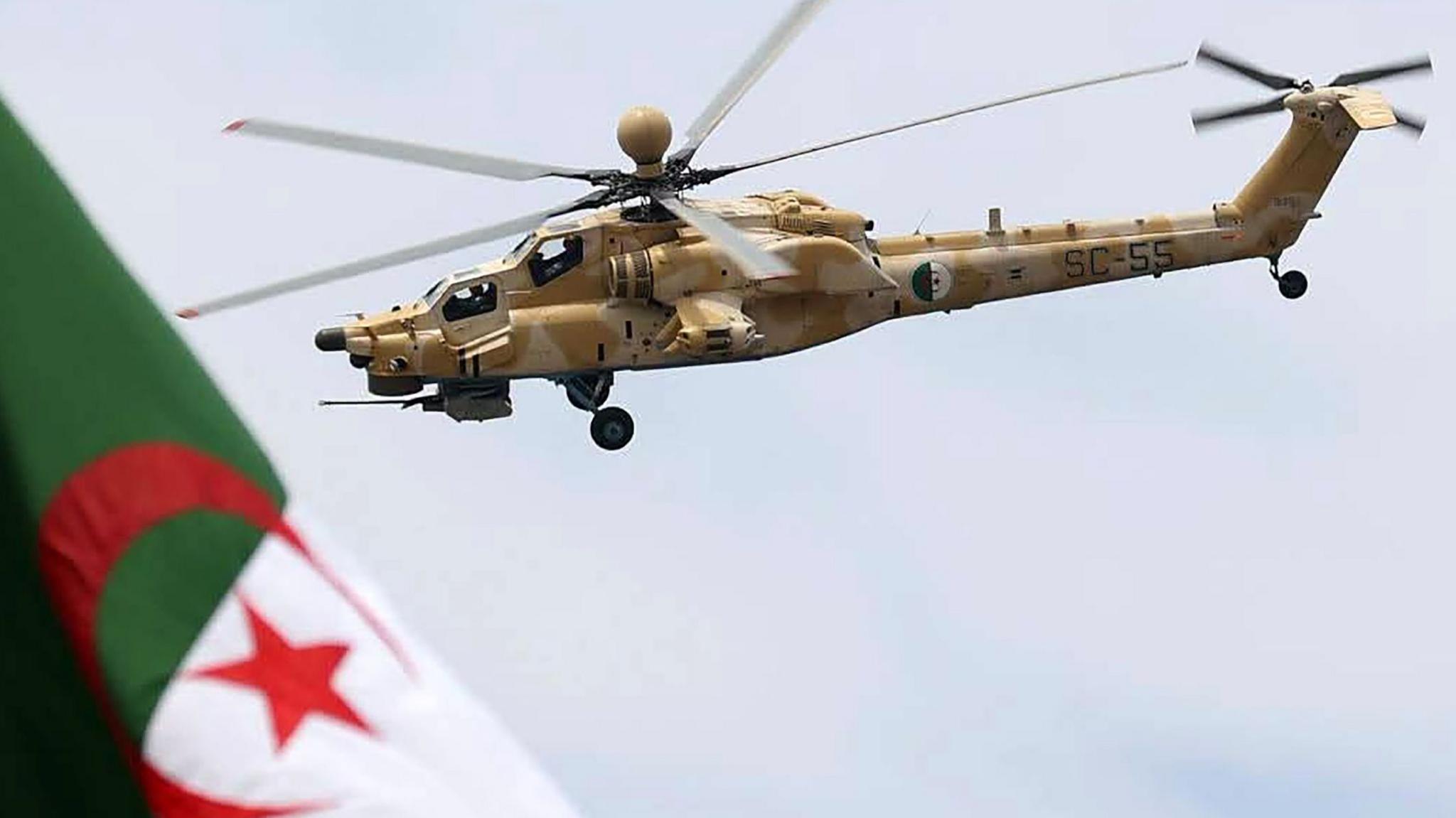 An Algerian military helicopter flies above a flag