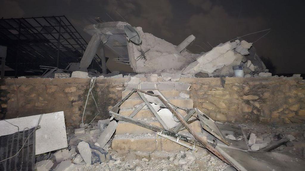 Rubble sits atop a small brick wall and six stairs.