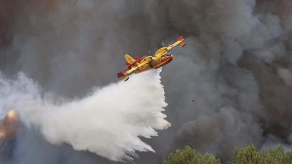 Canadair aircraft dropping water over a wildfire in Gironde
