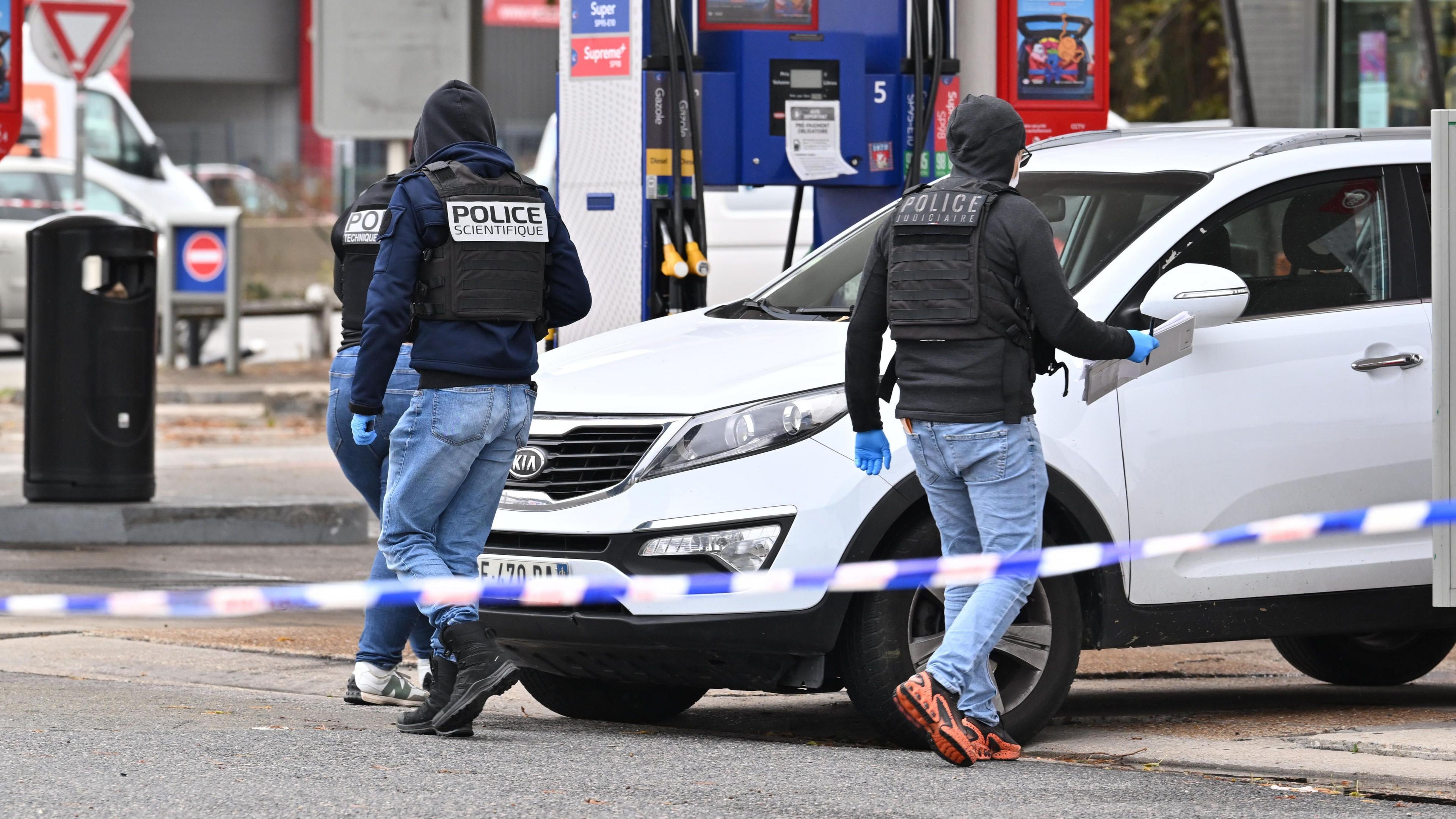 Forensic officers examine evidence at the site of a petrol station where a gunman opened fire from a vehicle, killing one person and injuring four others, in Trappes.