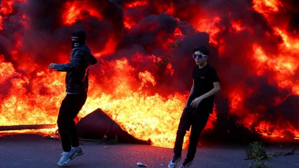 Students with masks ignite front of Tirana building